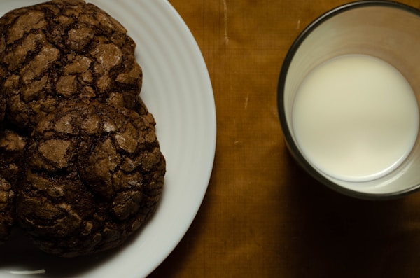 A plate of cookies next to a glass of milk