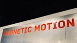 A metallic surface with the words 'MAGNETIC MOTION' written in bold red uppercase letters. The surface appears to be slightly scratched and the lighting highlights the text.