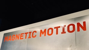 A metallic surface with the words 'MAGNETIC MOTION' written in bold red uppercase letters. The surface appears to be slightly scratched and the lighting highlights the text.