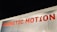 A metallic surface with the words 'MAGNETIC MOTION' written in bold red uppercase letters. The surface appears to be slightly scratched and the lighting highlights the text.