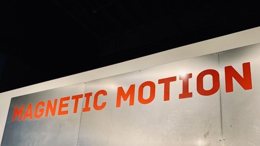 A metallic surface with the words 'MAGNETIC MOTION' written in bold red uppercase letters. The surface appears to be slightly scratched and the lighting highlights the text.