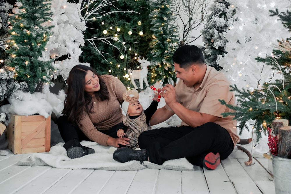 a man and a woman sitting on the floor near a christmas tree
