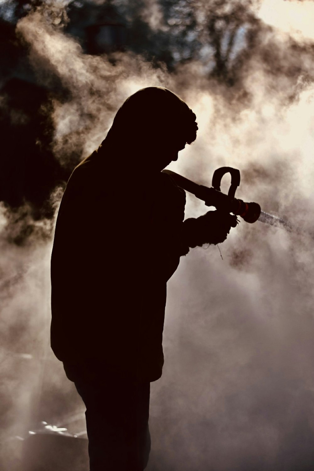 a silhouette of a man holding a water hose