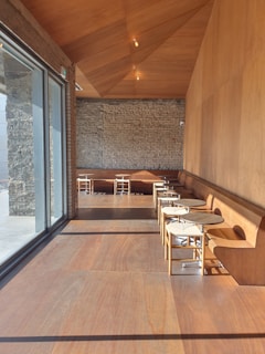 A minimalist cafe interior with warm beige and brown tones, featuring clean white walls and simple wooden furniture.