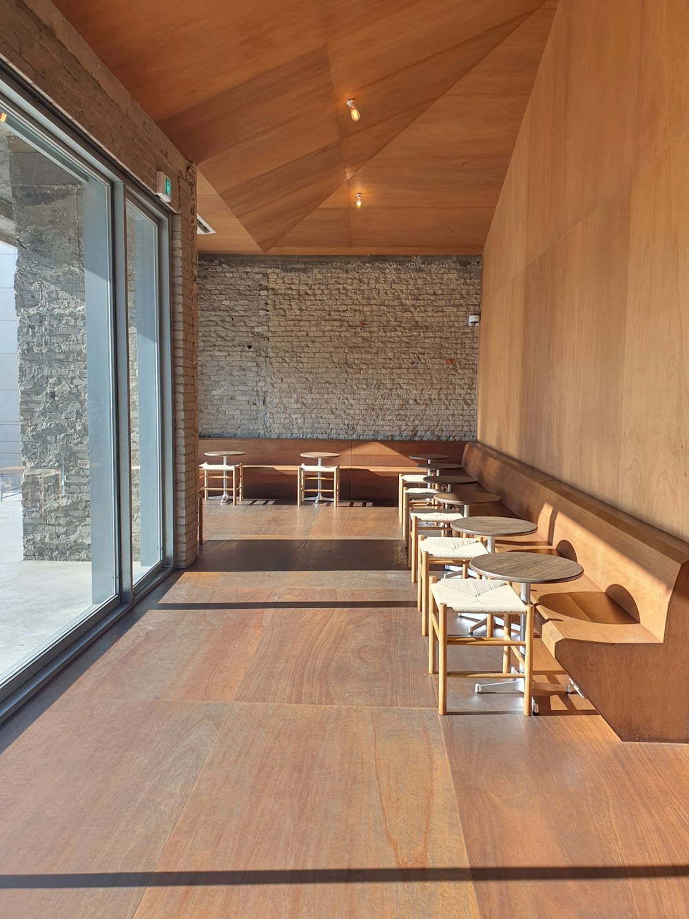 a restaurant with wooden tables and chairs next to a large window