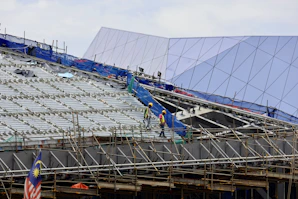 Construction workers from fz creators sdn. bhd. assembling scaffolding on a site.