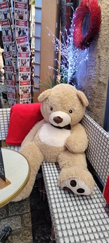 A cozy scene showing a large decorative teddy bear surrounded by soft lighting and gift boxes.