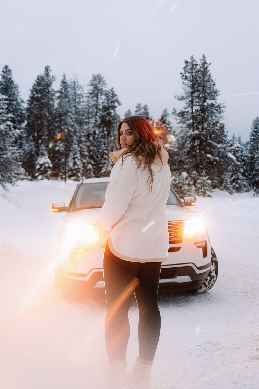 a woman standing next to a car in the snow