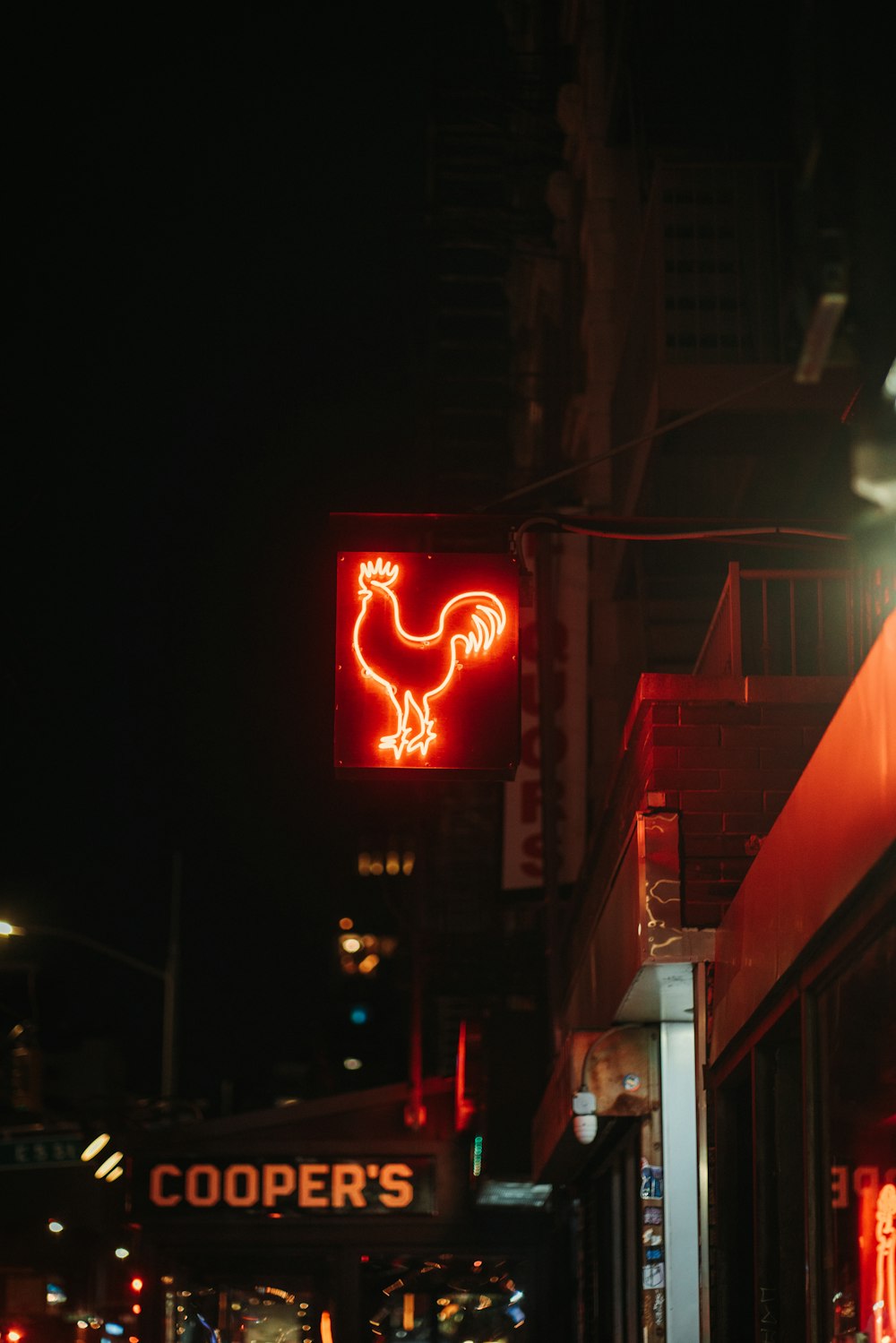 a neon rooster sign on the side of a building