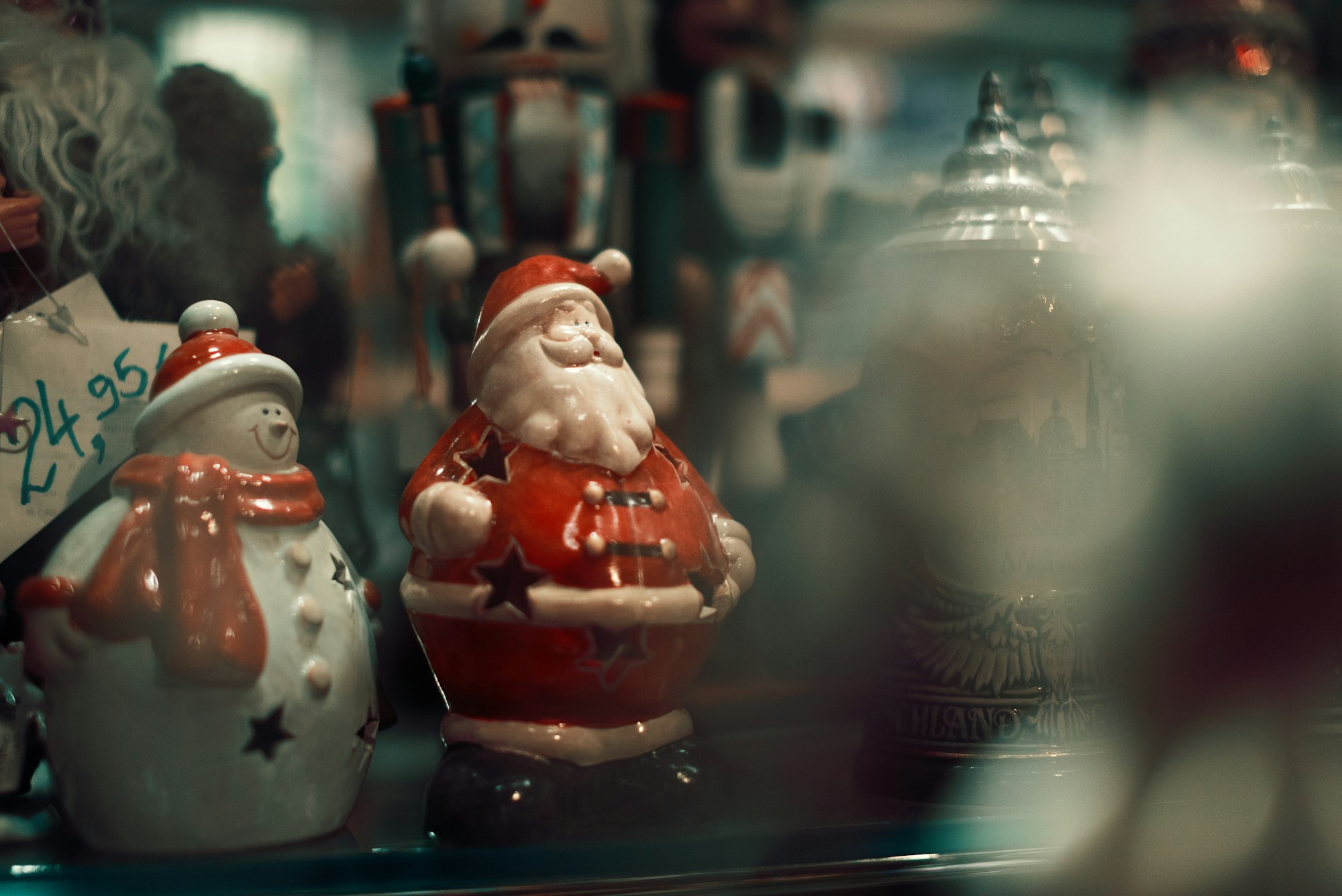 Winter holiday figures like Santa and a snowman on retail shop window shelf.