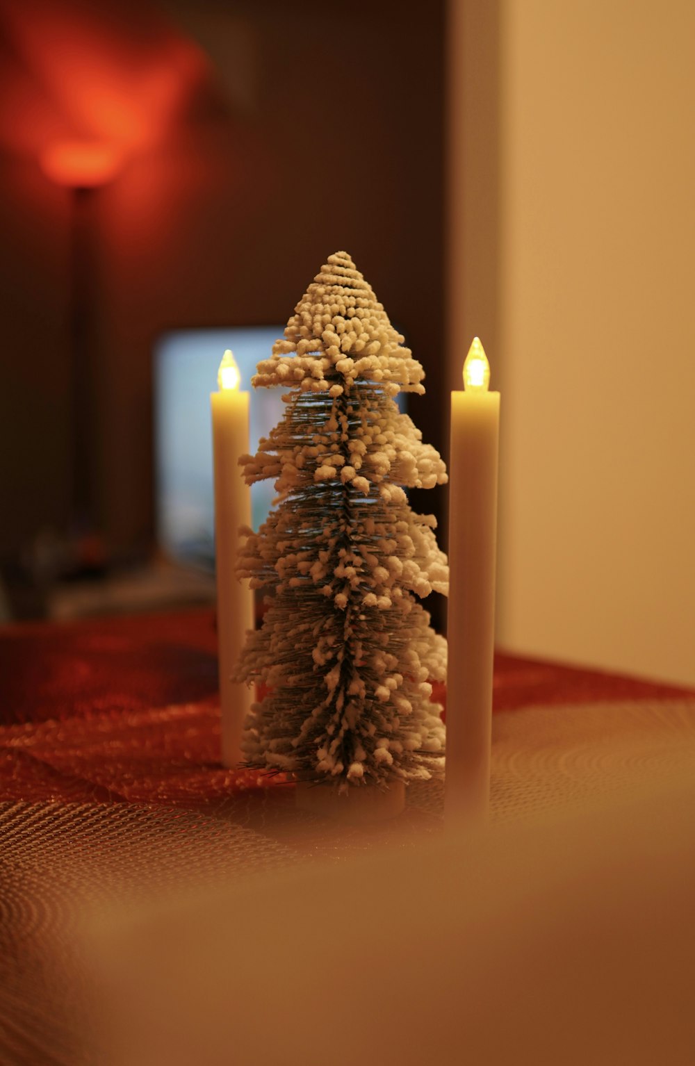 a small christmas tree sitting next to two candles