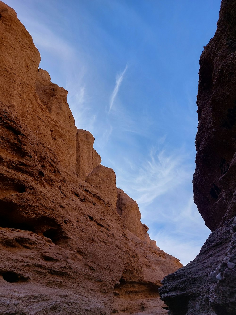 a person walking through a narrow slot in the desert