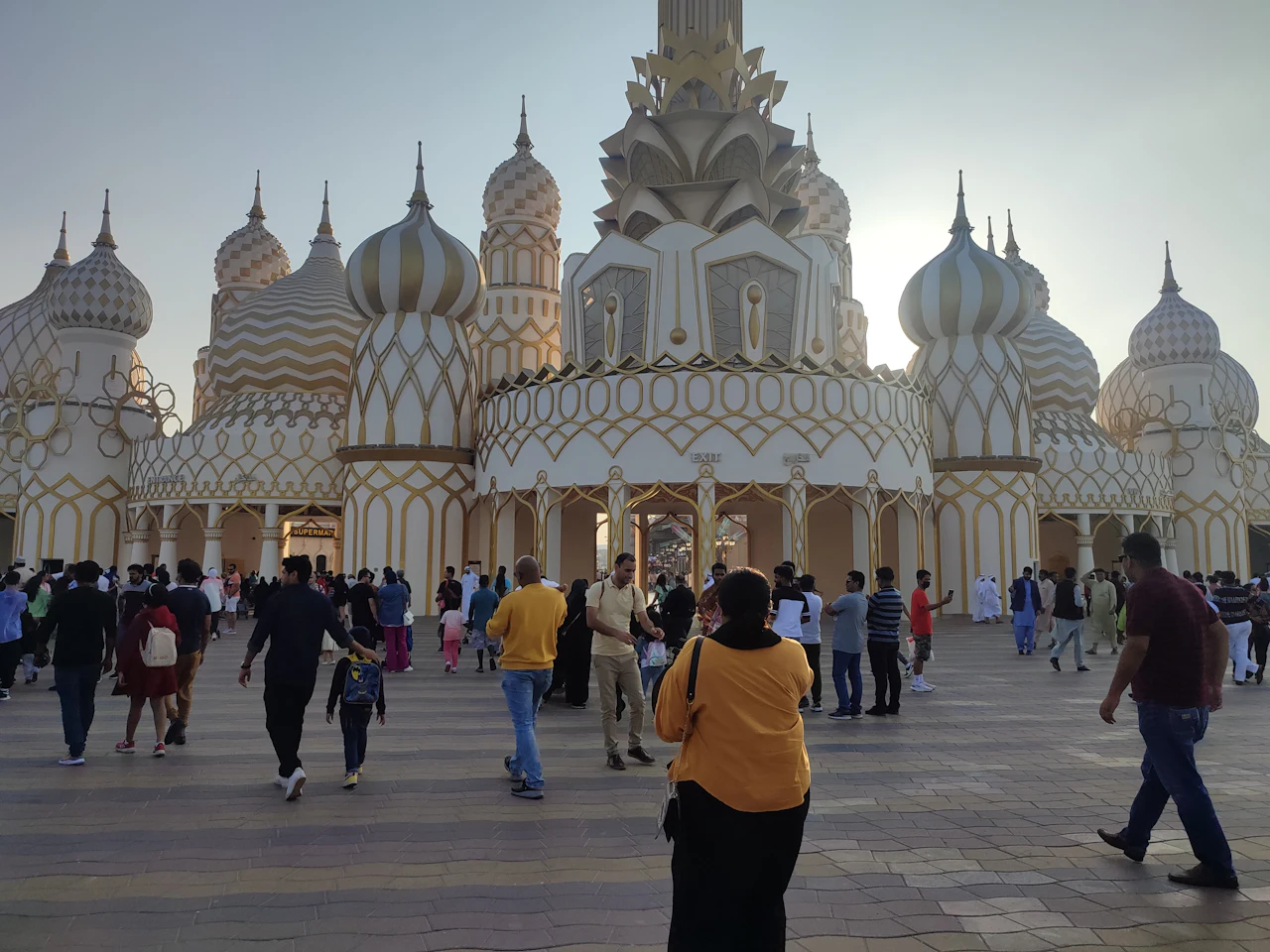 Visitors walking up to Global Village's Gate of the World in the late afternoon