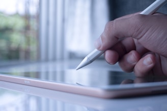 a person holding a pen and writing on a tablet