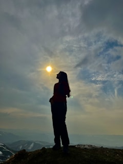 a person standing on top of a hill under a cloudy sky