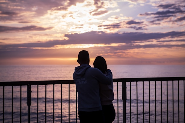 A smiling couple enjoying a sunset view from the balcony overlooking Sotogrande.