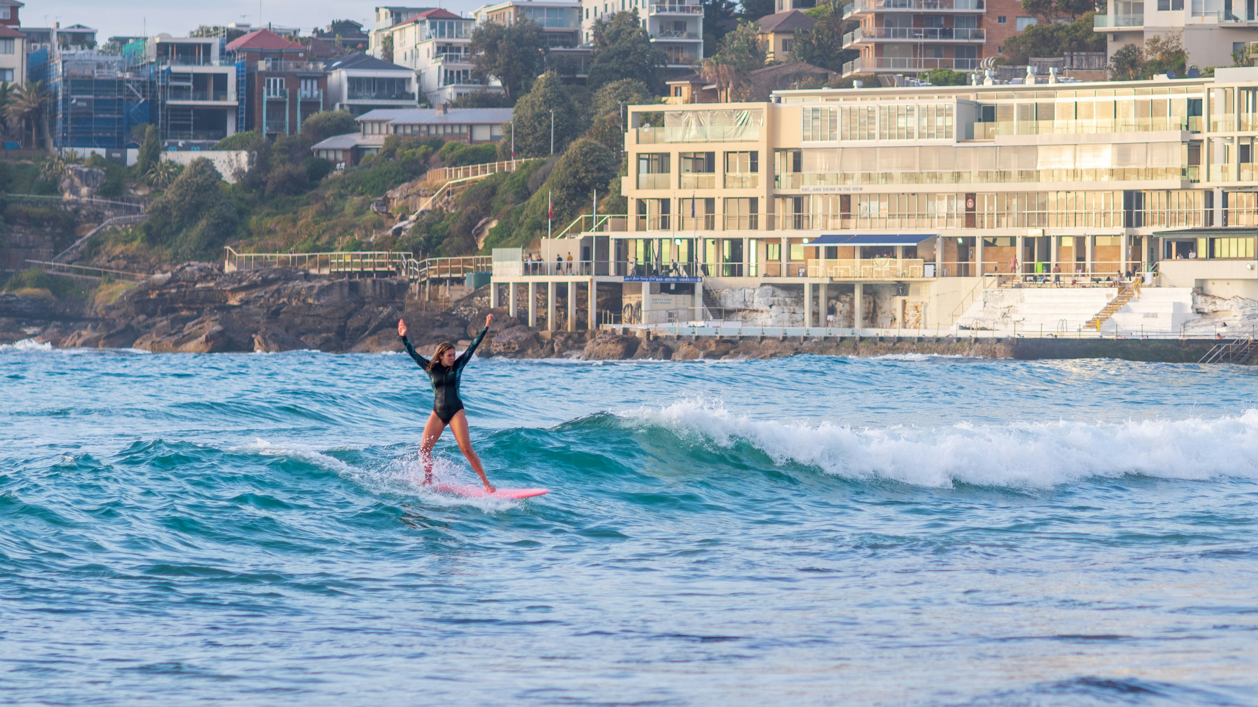 Portrait of a smiling woman in her 30s with sun-kissed hair, wearing a wetsuit