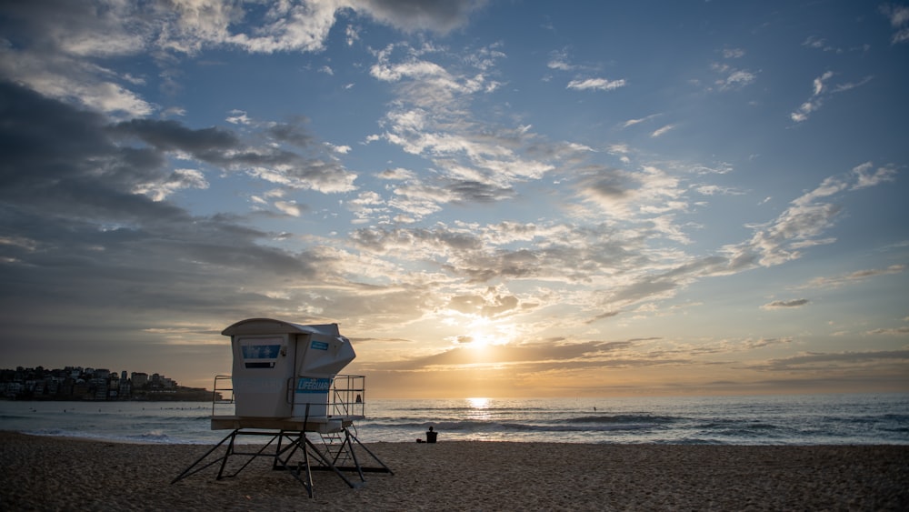 a lifeguard stand on the beach at sunset