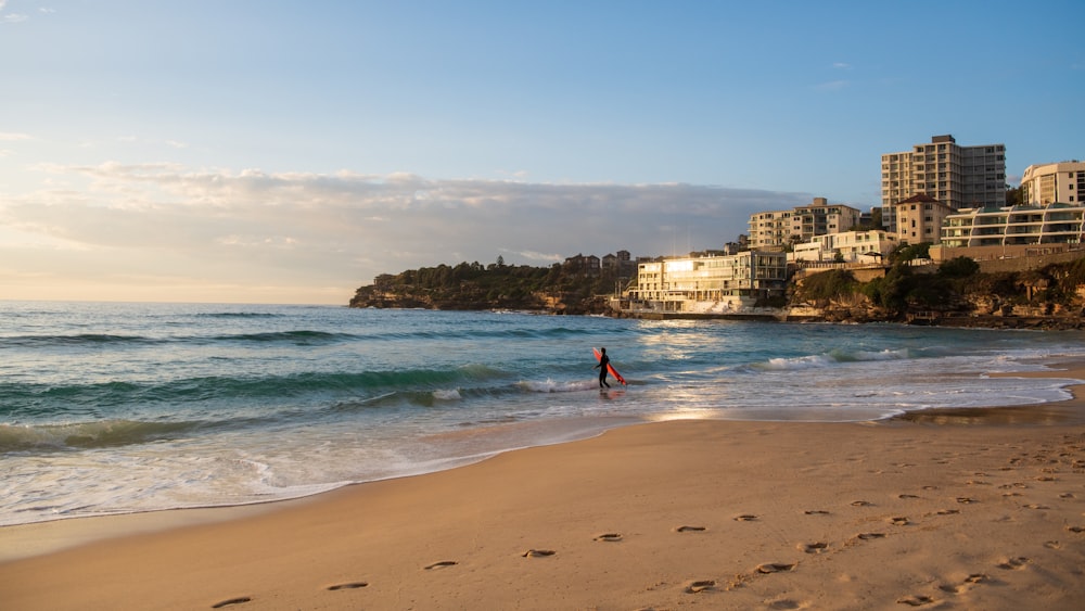 a person walking on a beach next to the ocean