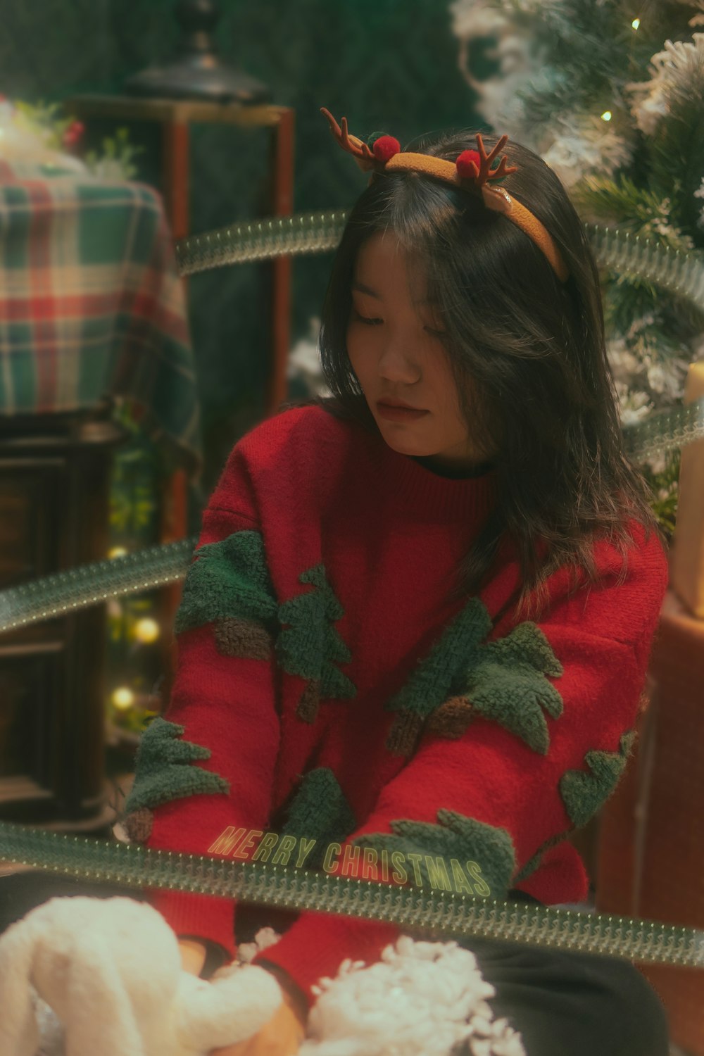 Une jeune fille assise devant un sapin de Noël
