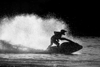 A sleek matte black jet ski adorned with gold accents gliding over dark waters under a twilight sky.