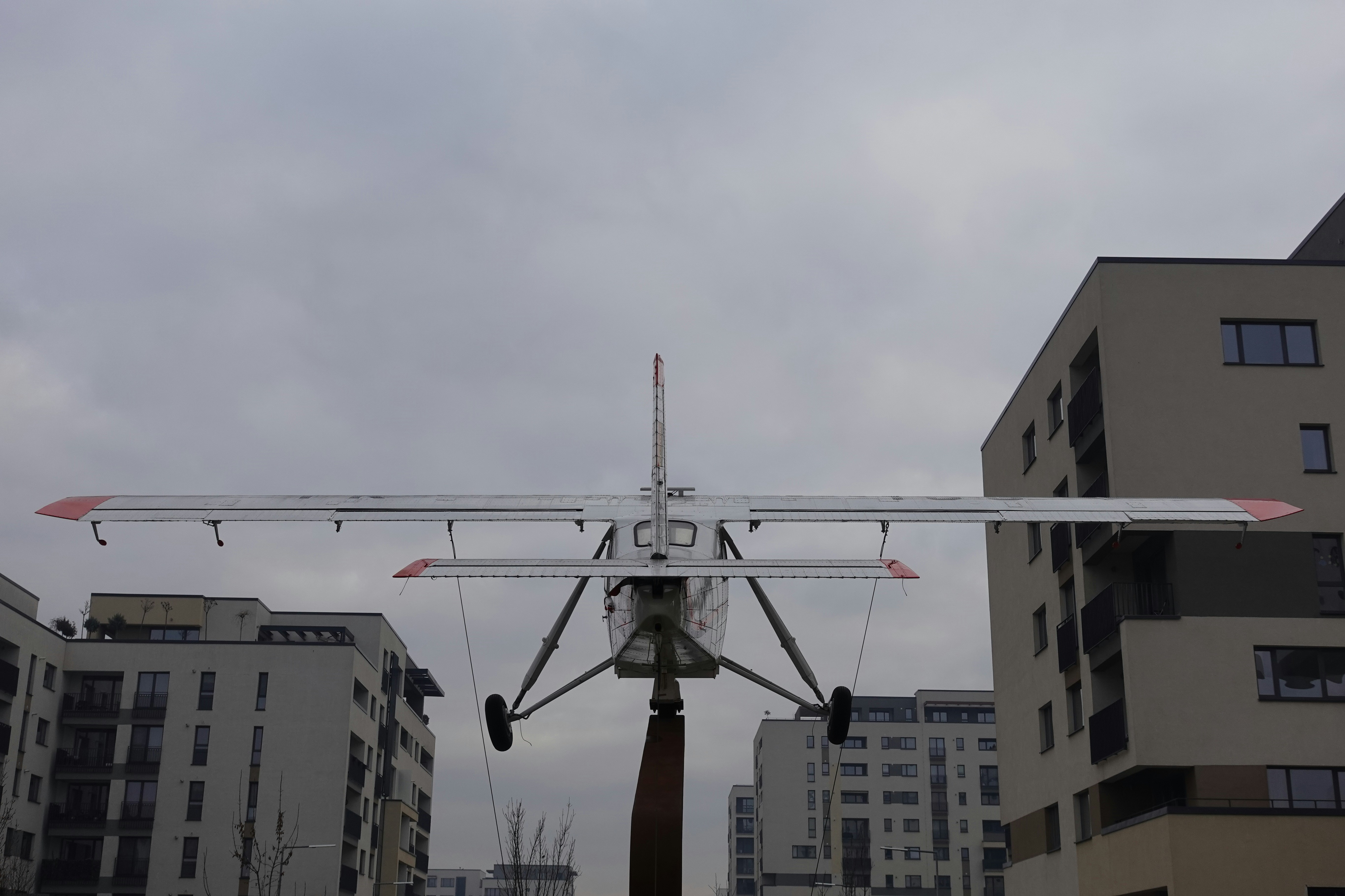 A small airplane flying over a city next to tall buildings