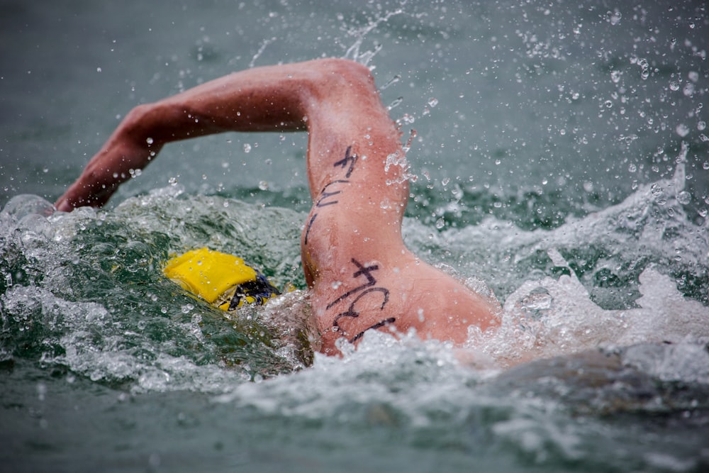 a man swimming in the water with a yellow frisbee