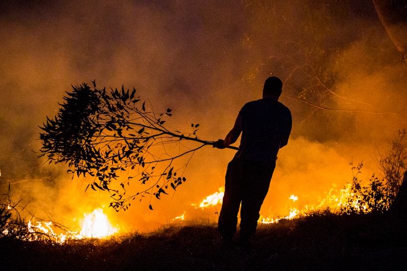 a man holding a stick in front of a fire