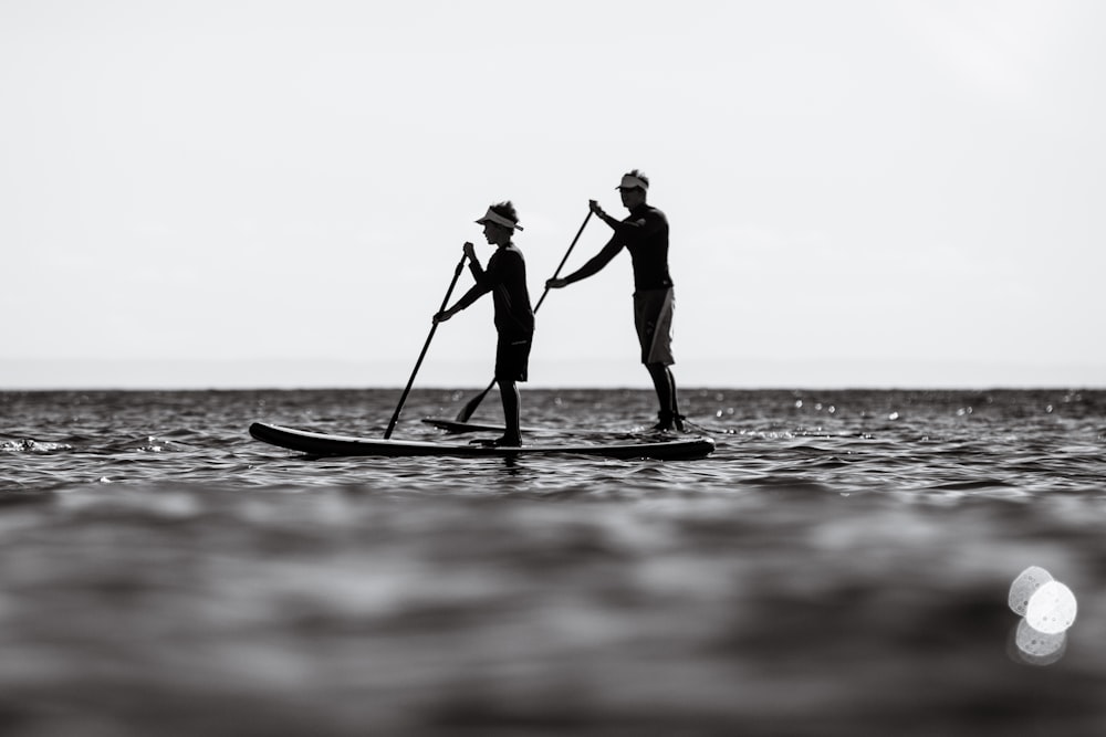 a couple of people standing on top of a paddle board