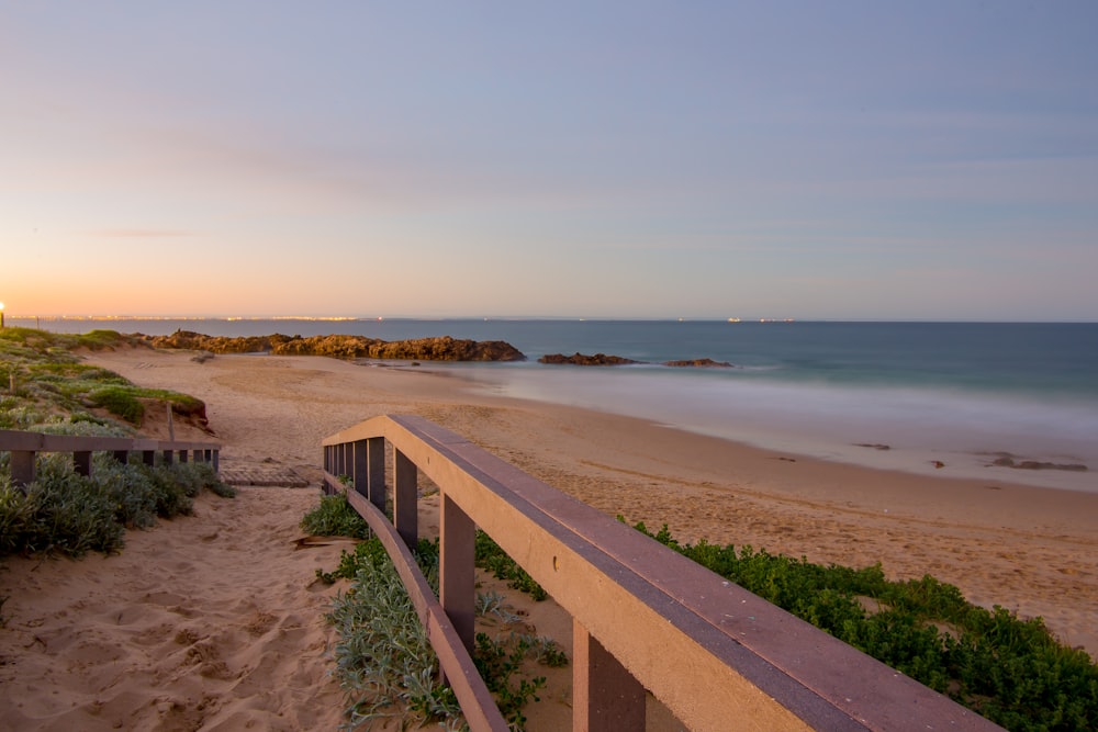 a view of a beach from a balcony at sunset