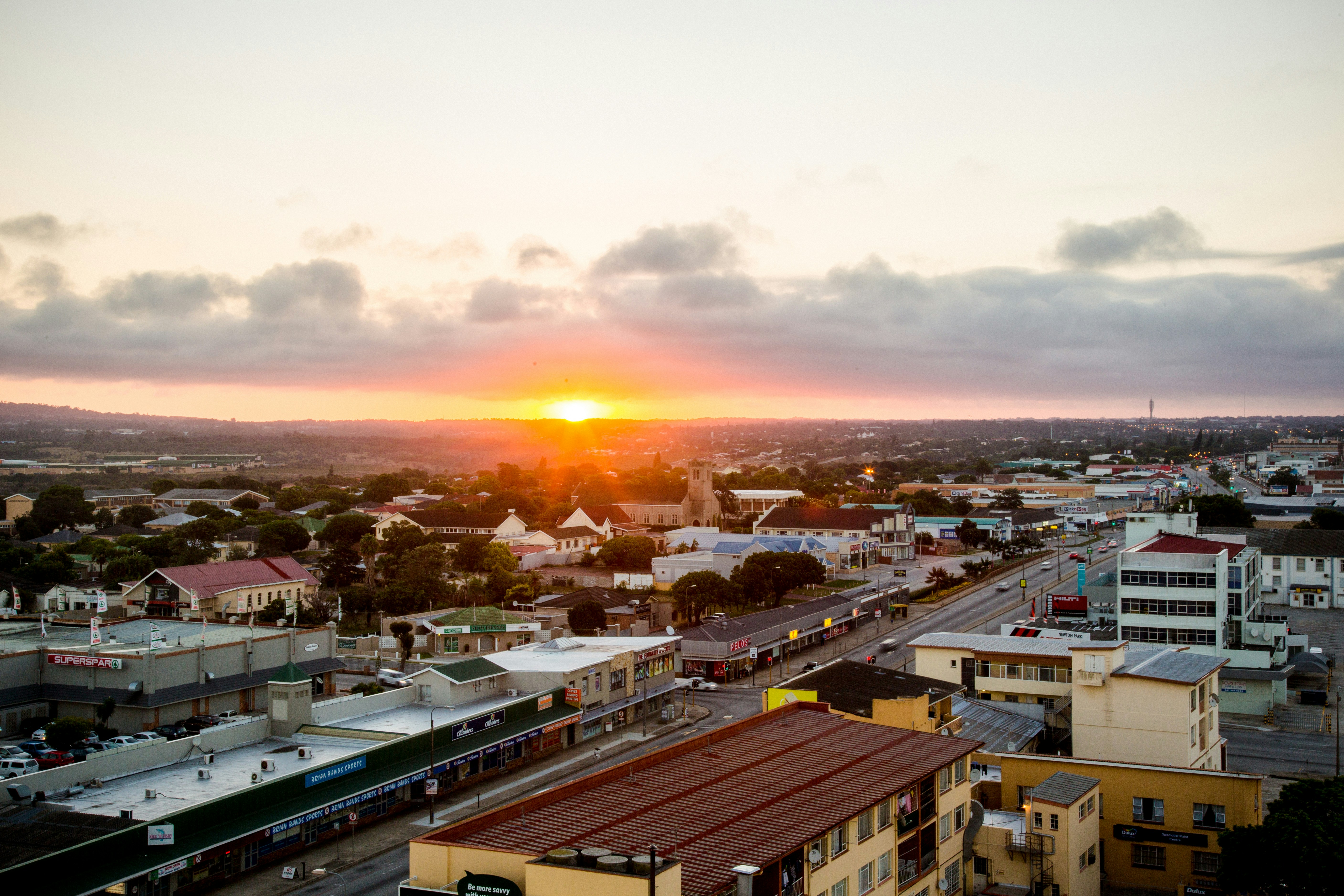 the sun is setting over a city with tall buildings
