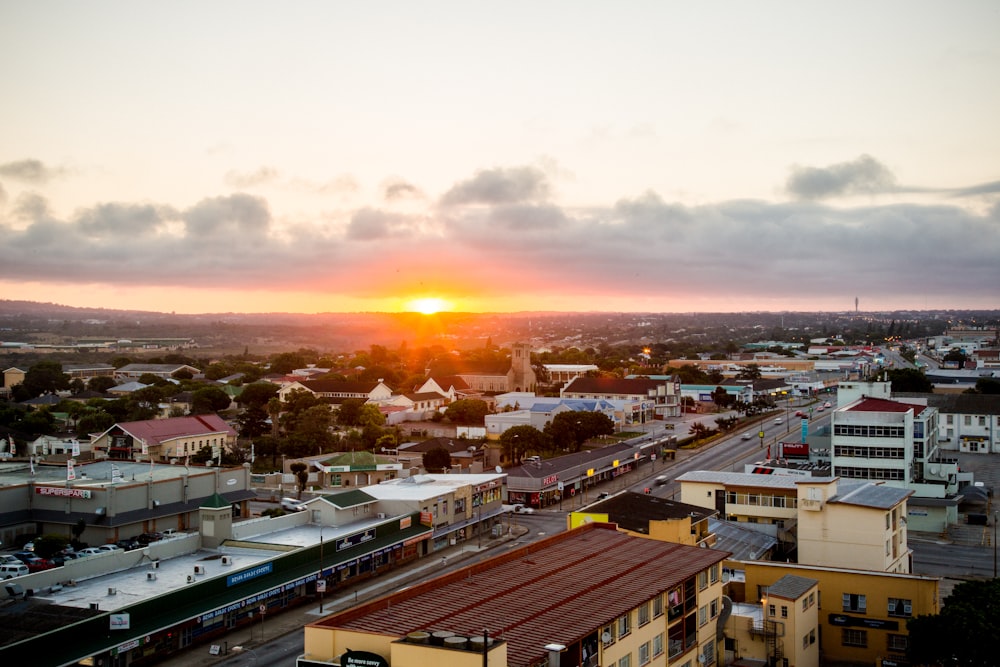 the sun is setting over a city with tall buildings