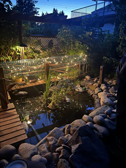 A serene Okanagan backyard softly illuminated by warm soffit and landscape lighting at dusk.