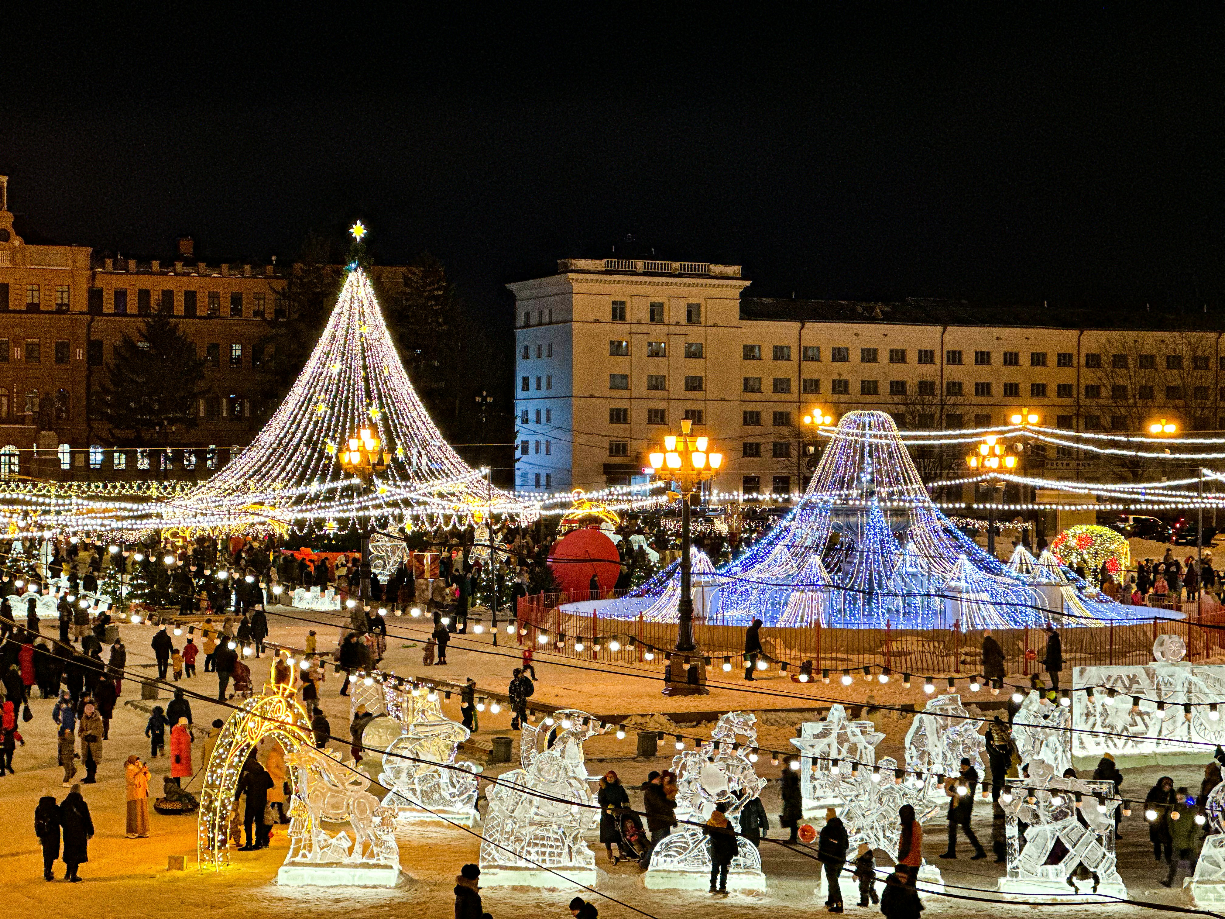 a group of people standing around a christmas tree, 