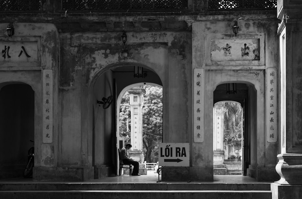 Una foto en blanco y negro de un hombre sentado en un banco