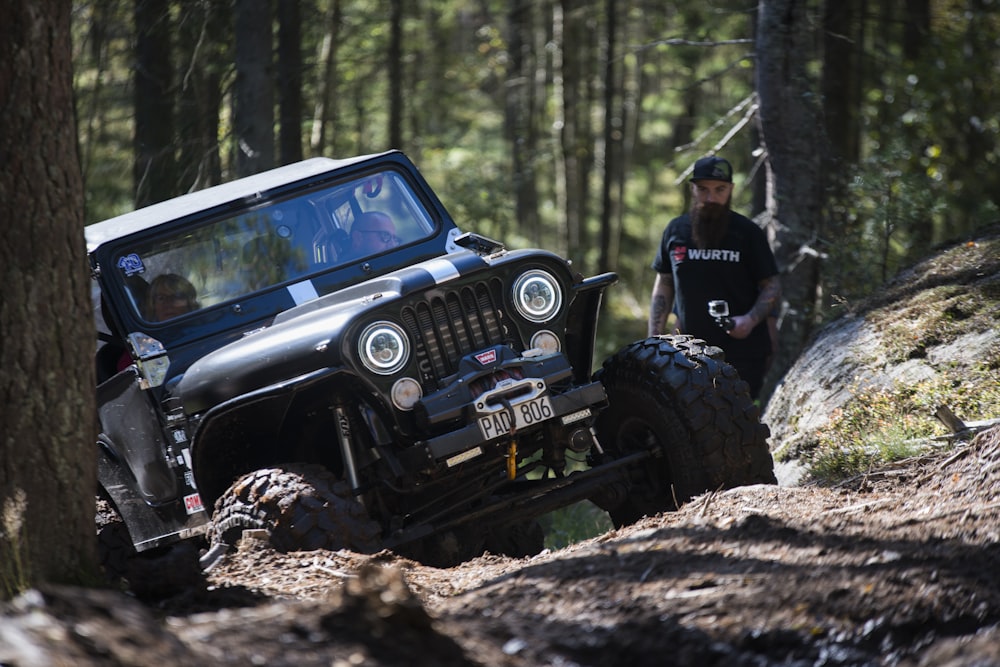 a black jeep driving through a forest filled with trees