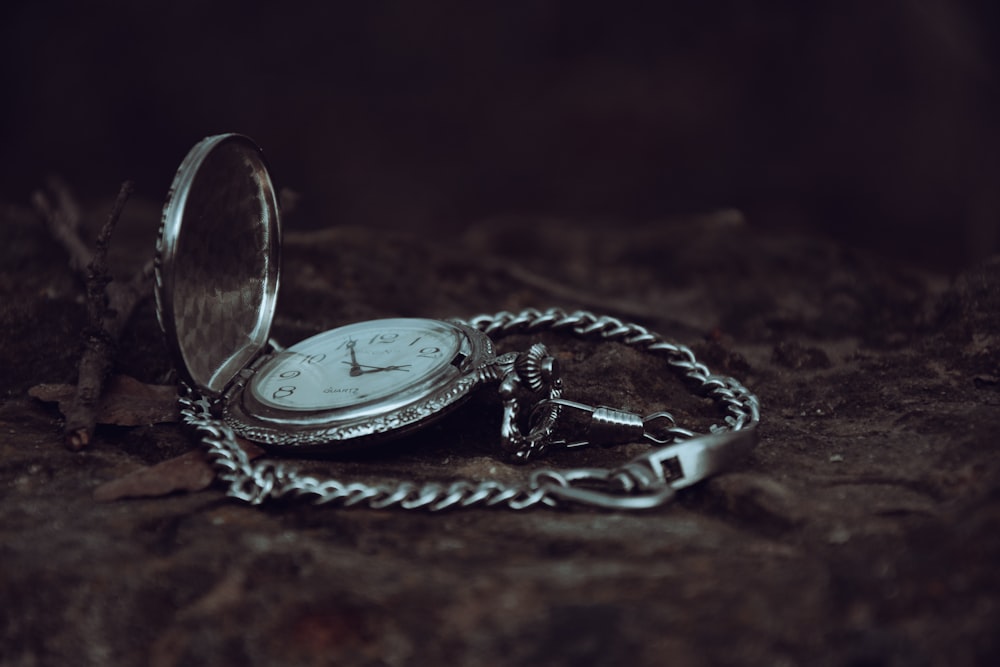 a pocket watch sitting on top of a rock