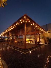A cozy backyard illuminated by warm string lights draped over a wooden pergola at dusk.