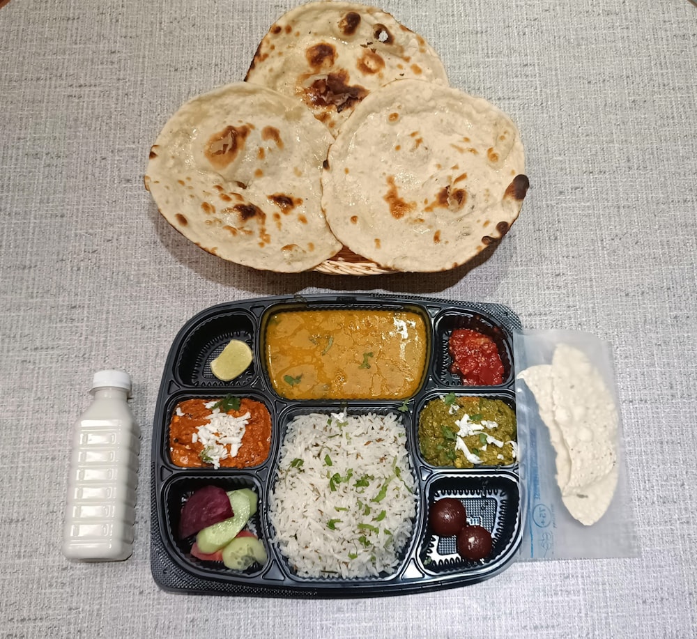 a tray of food with rice, sauces, and pita bread