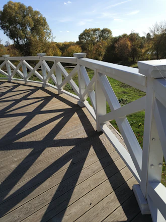 A sturdy backyard deck gleaming under a clear sky with autumn leaves scattered around.