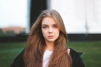 a woman with long hair standing in a field