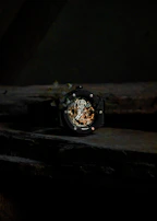 A dramatic overhead shot of a black and gold watch with intricate detailing, casting deep shadows.