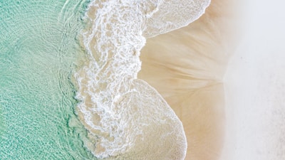 Aerial view of a serene beach with turquoise water and gentle waves.