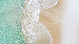 Aerial view of a serene beach with turquoise water and gentle waves.
