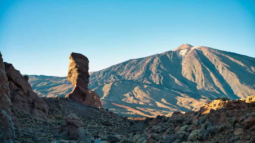 a mountain range with a rock formation in the foreground