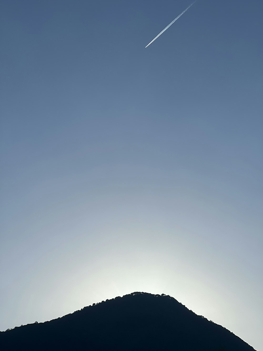 a plane flying in the sky over a mountain