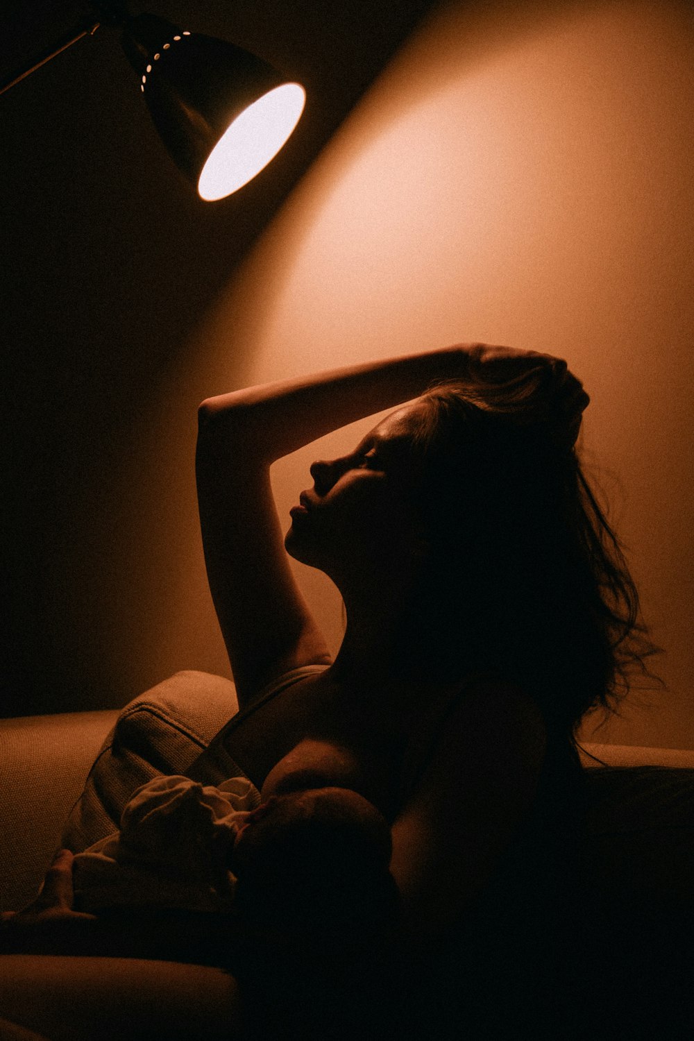 a woman laying in a bed under a lamp