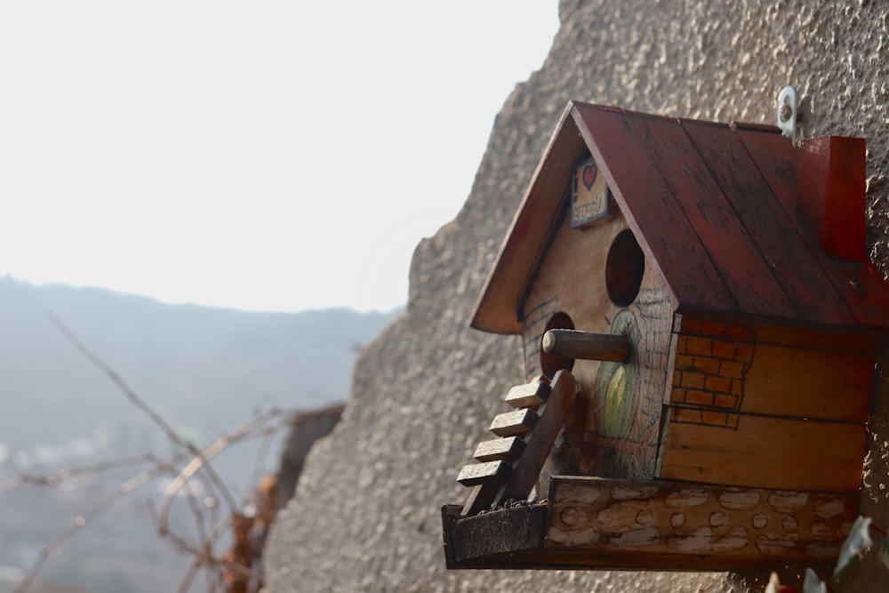 a bird house hanging from the side of a stone wall