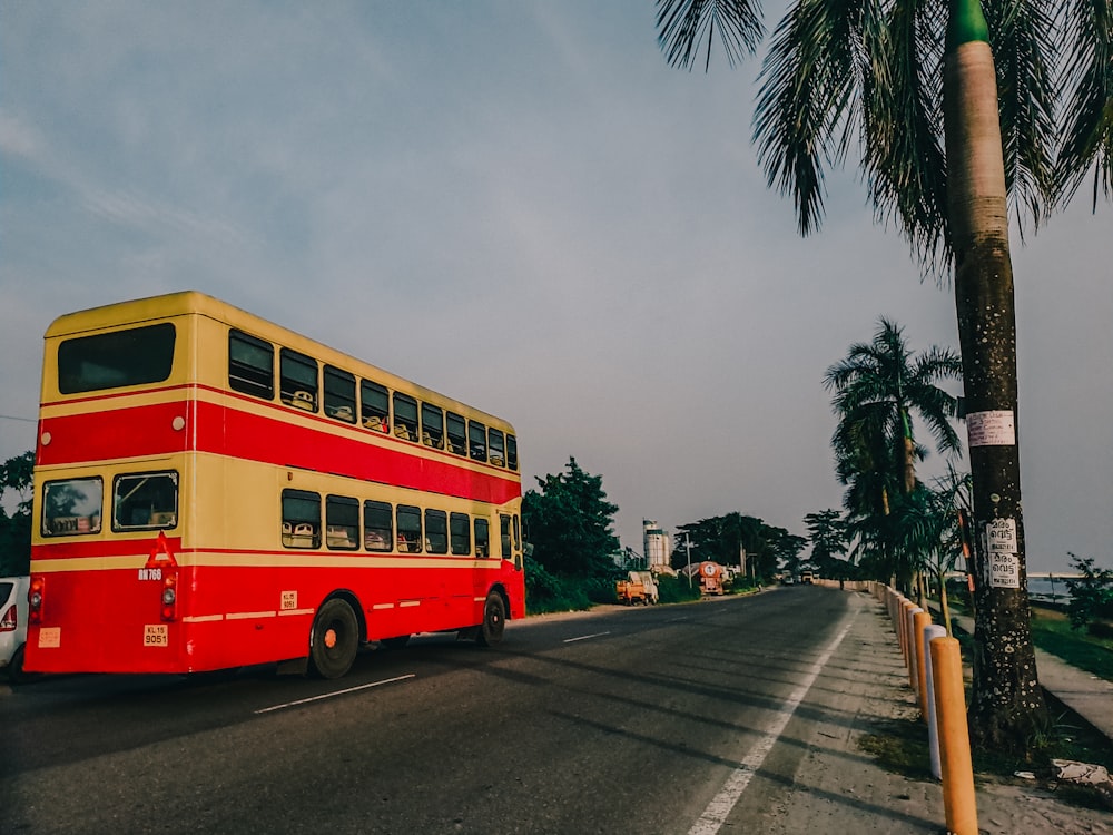 a red and yellow double decker bus driving down a street
