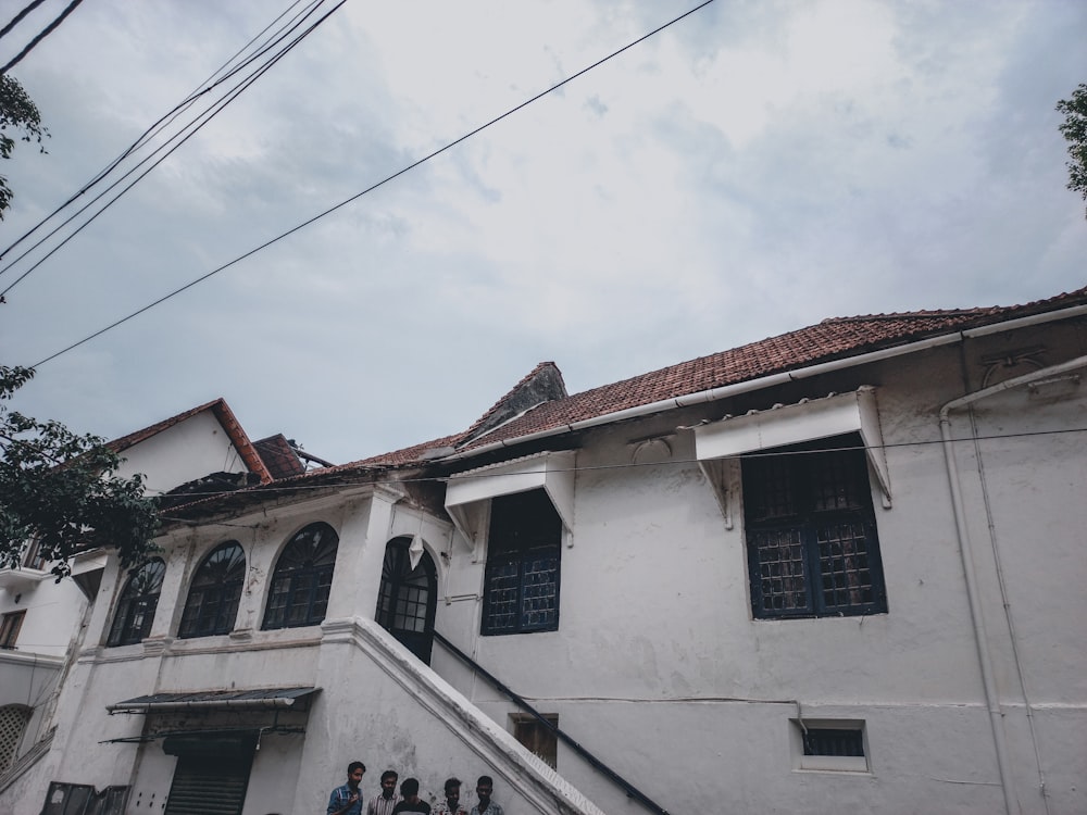 a group of people standing outside of a white building